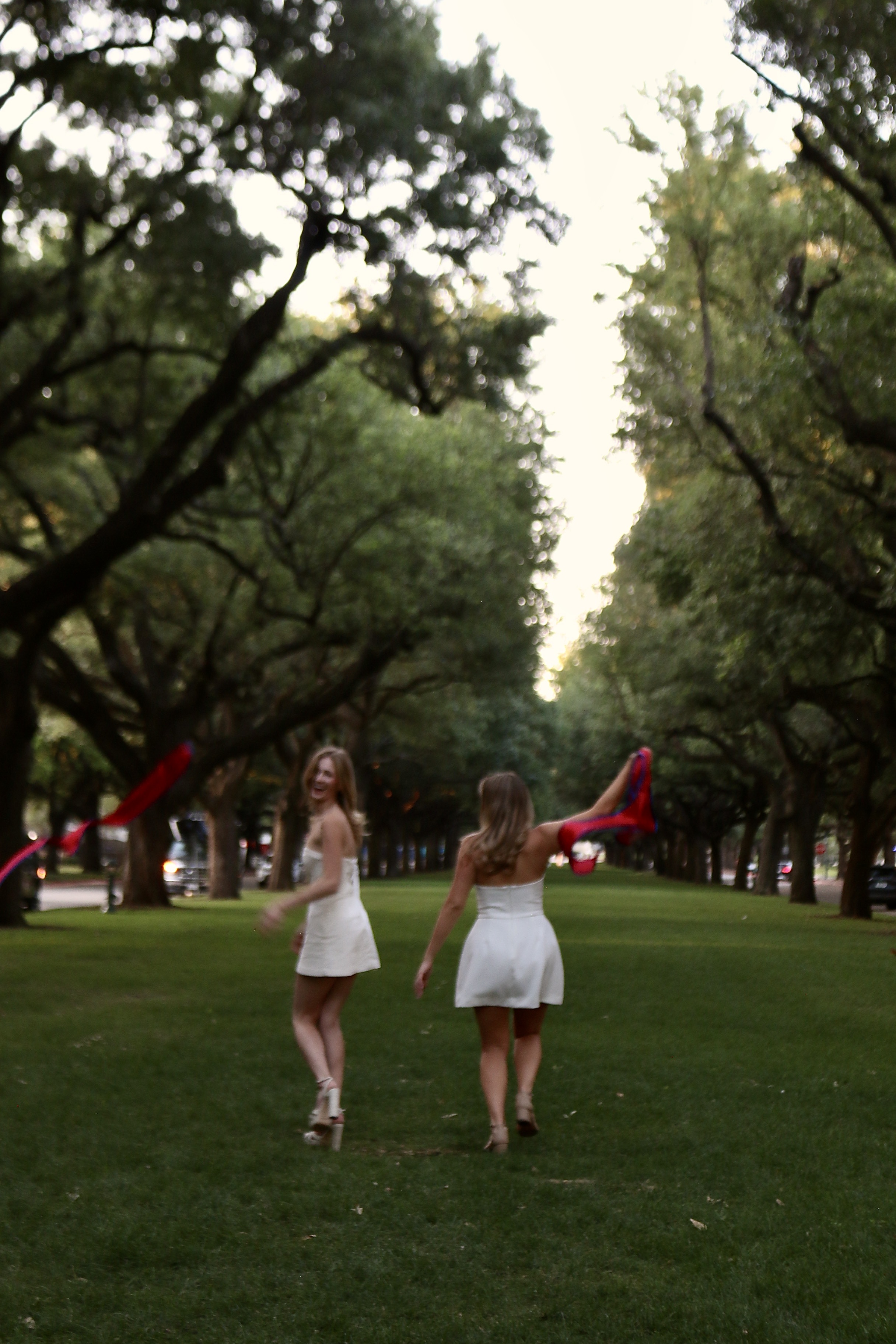 Two graduates walking through trees